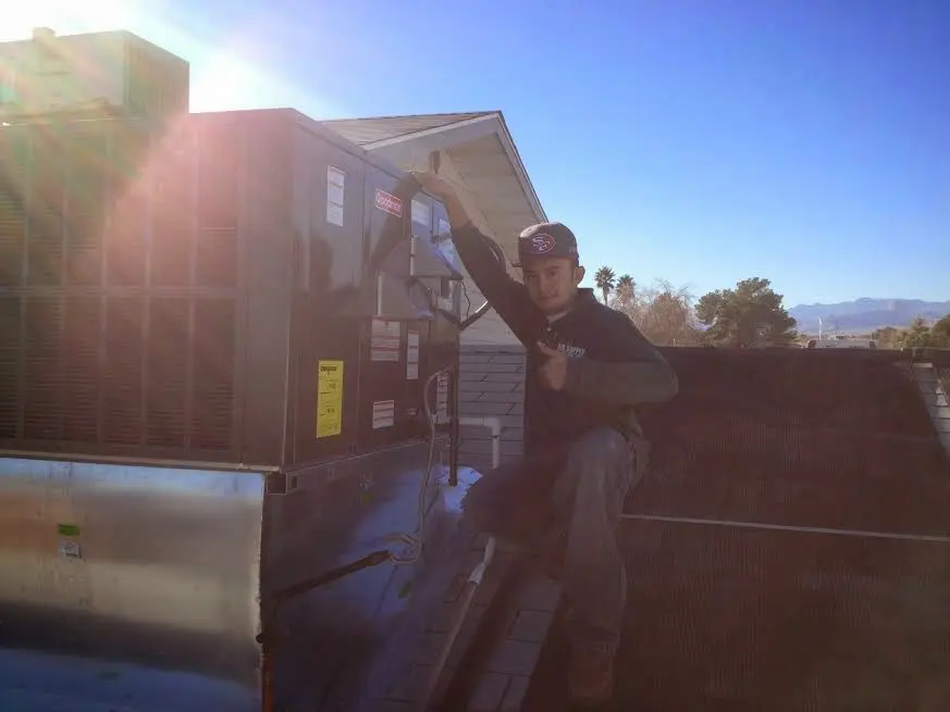 HVAC technician performing Heat Pump Repair on a rooftop unit in Perinton