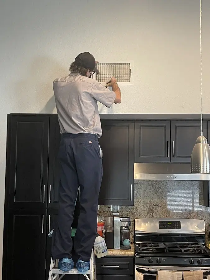 Technician inspecting an air vent during HVAC service in Perinton